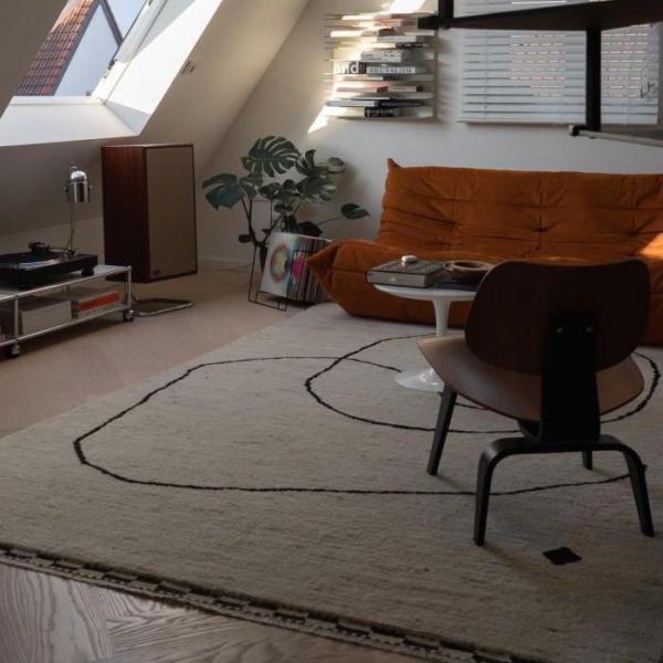 Tapis stylé en beige avec des lignes noires en accent dans un look rétro pour le salon.